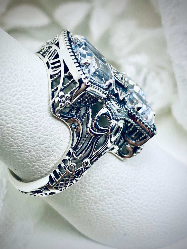 White CZ Ring, With White CZ Inset gem in the center, Sterling Silver Filigree, Silver Embrace Jewelry, D595 Versailles Ring. A 925 sterling silver ring with four central CZ gems, adorned with a bow, a stone, petite blossoms and two bows on the band. The ring showcases French/Baroque style with meticulous detailing.