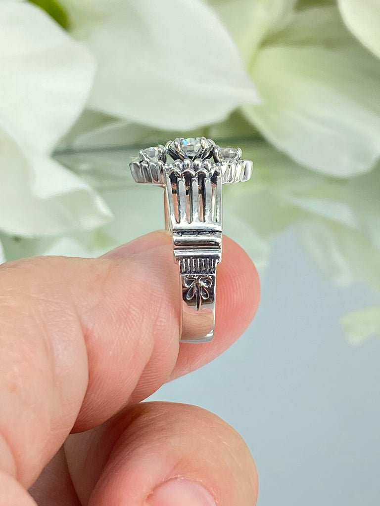 a person holding a silver ring a three stone ring with a White CZ center. Sterling Silver Art Deco Filigree, fine detail, Silver Embrace Jewelry, Xanadu D164