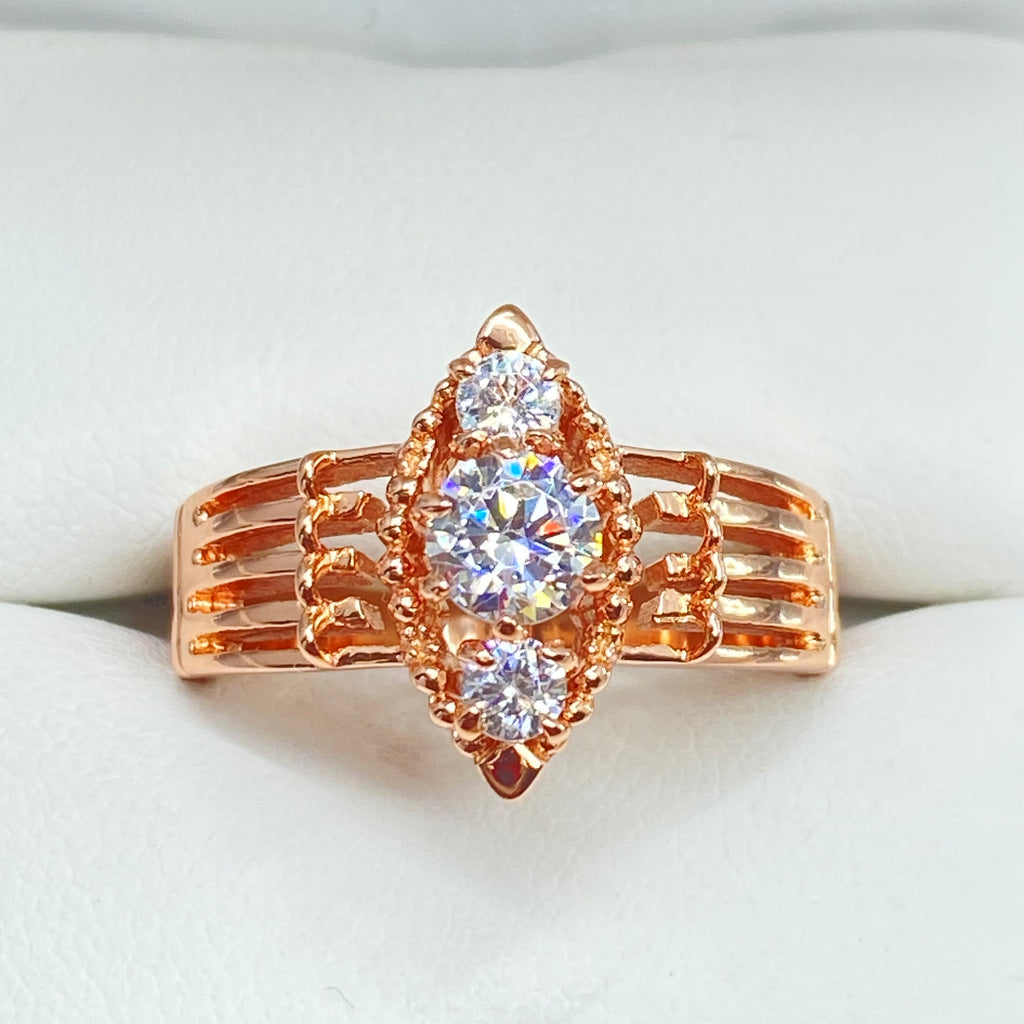 Rose gold ring with multiple sparkling gems on a light background, a three stone ring with a White CZ center. Rose Gold plated Sterling Silver Art Deco Filigree, fine detail, Silver Embrace Jewelry, Xanadu D164