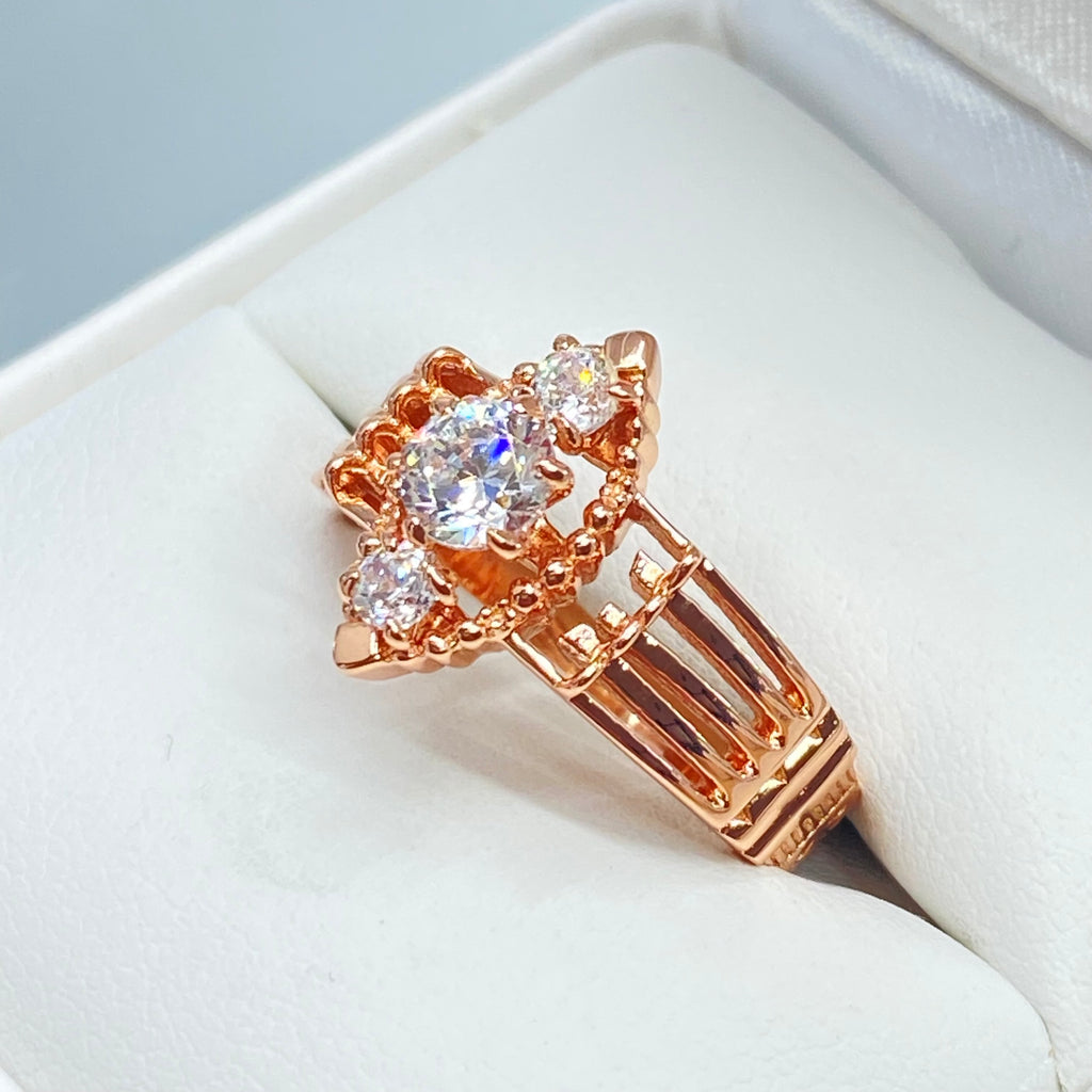 Rose gold ring with multiple sparkling gems on a light background, a three stone ring with a White CZ center. Rose Gold plated Sterling Silver Art Deco Filigree, fine detail, Silver Embrace Jewelry, Xanadu D164