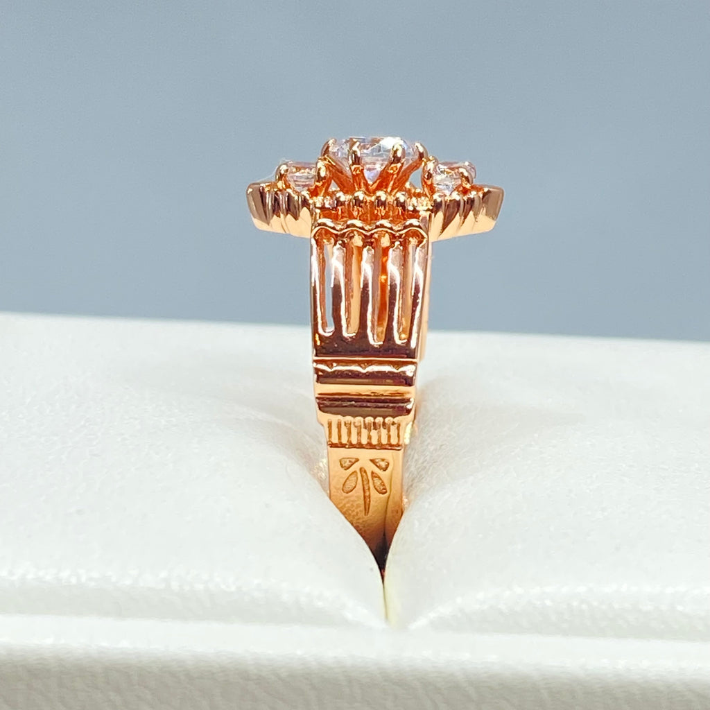 Rose gold ring with multiple sparkling gems on a light background, a three stone ring with a White CZ center. Rose Gold plated Sterling Silver Art Deco Filigree, fine detail, Silver Embrace Jewelry, Xanadu D164