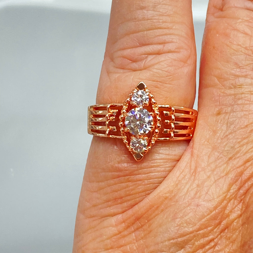 Rose gold ring with multiple sparkling gems on a Hand, a three stone ring with a White CZ center. Rose Gold plated Sterling Silver Art Deco Filigree, fine detail, Silver Embrace Jewelry, Xanadu D164