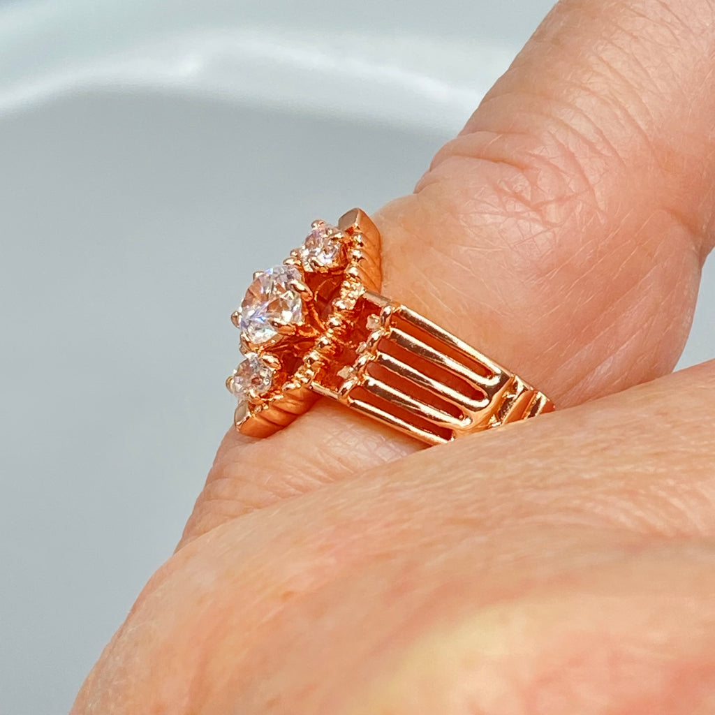 Rose gold ring with multiple sparkling gems on a hand, a three stone ring with a White CZ center. Rose Gold plated Sterling Silver Art Deco Filigree, fine detail, Silver Embrace Jewelry, Xanadu D164