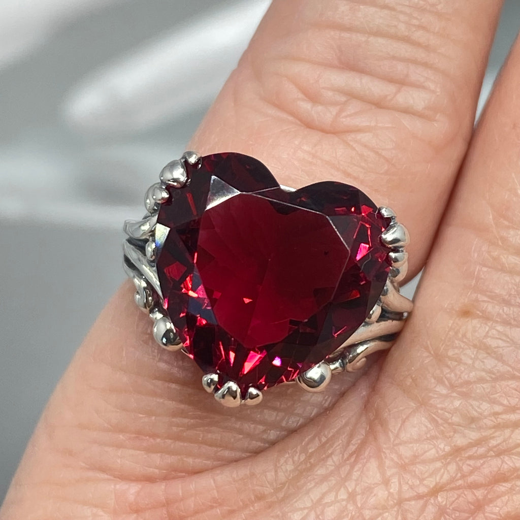 Heart-shaped red gemstone ring on a finger with a blurred background, Ruby Ring, Heart Ring, Sterling Silver Filigree, silver Embrace Jewelry, D213