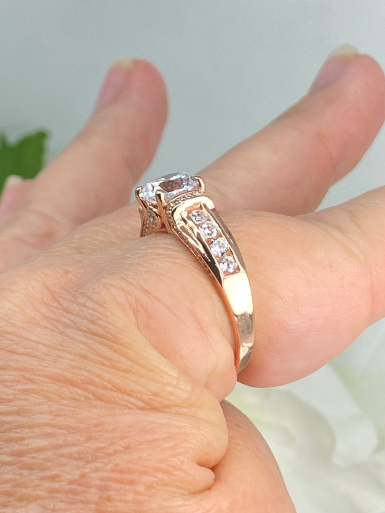 white CZ art deco rose gold ring, center stone is round cut white Cubic Zirconia, there are two trails of white CZ accents traveling up the sides of the band and two more trails of white CZs on each side of the band partially encircling the center stone, finally there are two accent white CZs on each of the remaining sides of the center stone, Silver Embrace Jewelry, D220, Deco Inlay, White CZ Ring