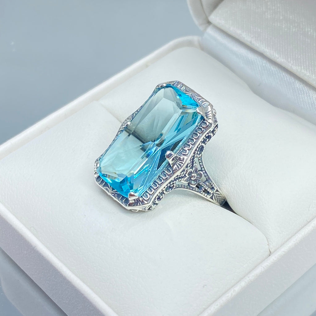 Simulated Aquamarine Ring, Edwardian Jewelry, Sterling silver filigree, Silver Embrace Jewelry D232, Aquamarine Silver ring with a large blue gemstone on a white cushion in an open jewelry box.