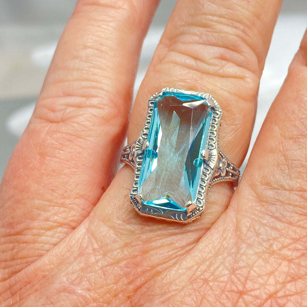 Simulated Aquamarine Ring, Edwardian Jewelry, Sterling silver filigree, Silver Embrace Jewelry D232, Aquamarine Ring with a blue gemstone on a finger