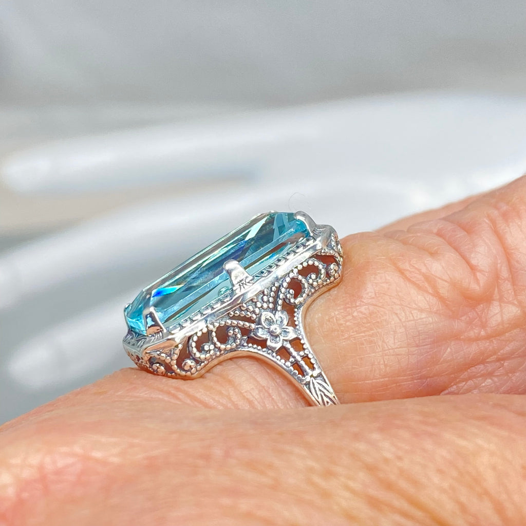  Simulated Aquamarine Ring, Edwardian Jewelry, Sterling silver filigree, Silver Embrace Jewelry D232, Aquamarine Silver ring with a large blue gemstone on a finger against a blurred background