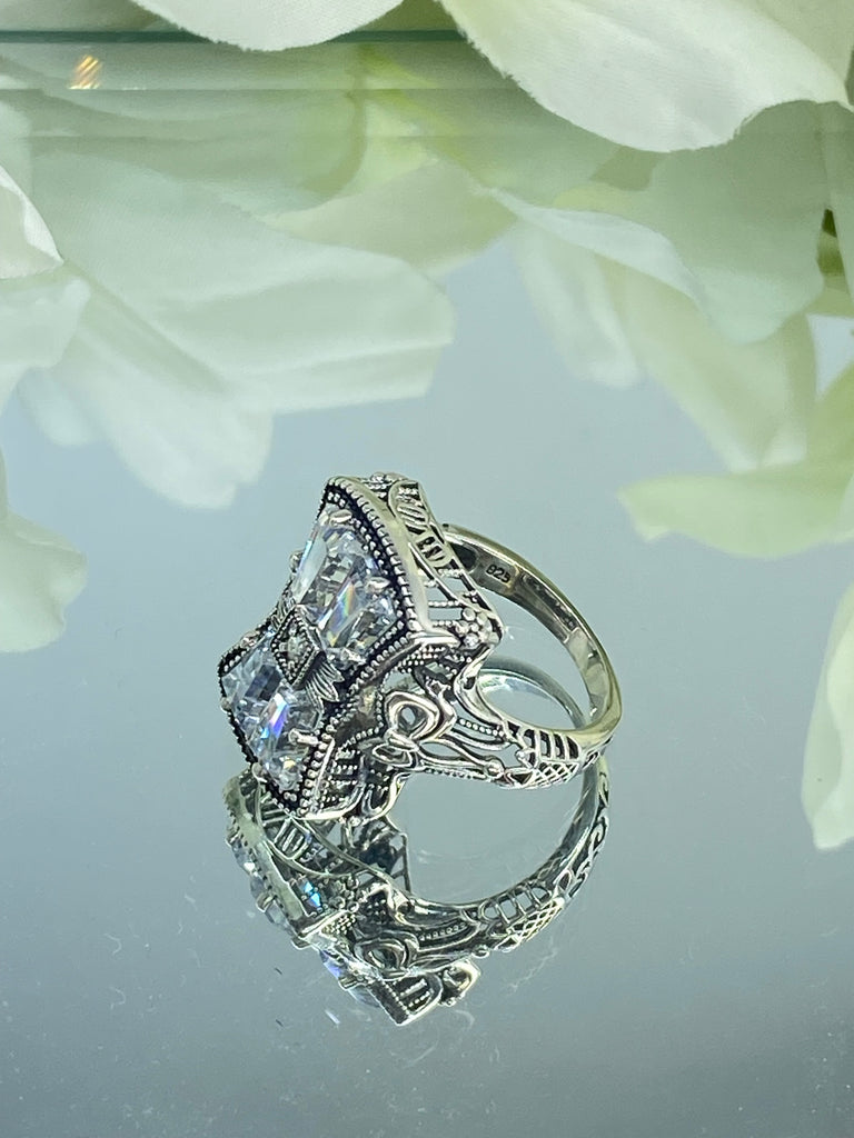 White CZ Ring, With Moissanite Inset gem in the center, Sterling Silver Filigree, Silver Embrace Jewelry, D595 Versailles Ring. A 925 sterling silver ring with four central CZ gems, adorned with a bow, a stone, petite blossoms and two bows on the band. The ring showcases French/Baroque style with meticulous detailing.