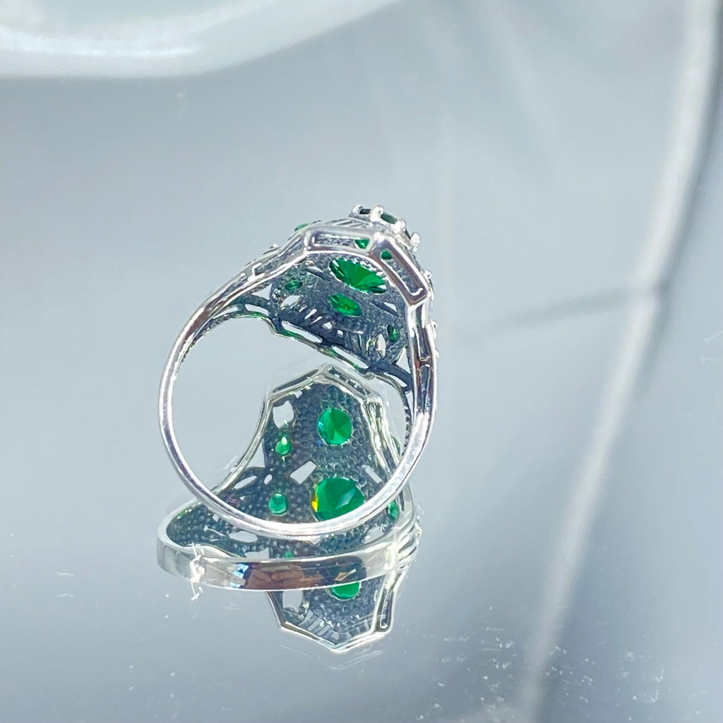 Emerald Ring with 9 Gems, sterling silver filigree, D69, 9-Gem Ring, Silver Embrace jewelry, Silver ring with green gemstones on a reflective surface