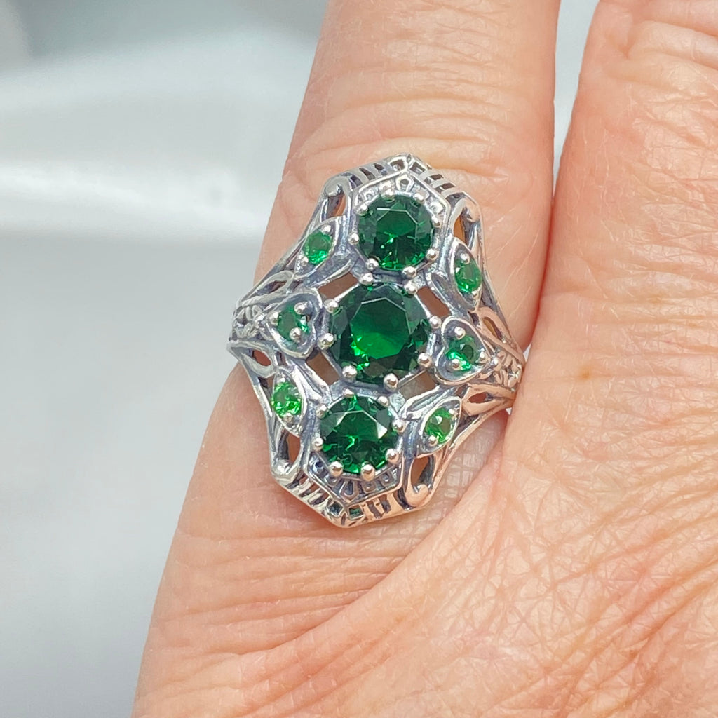Emerald Ring with 9 Gems, sterling silver filigree, D69, 9-Gem Ring, Silver Embrace jewelry, Silver ring with green gemstones on a finger against a neutral background