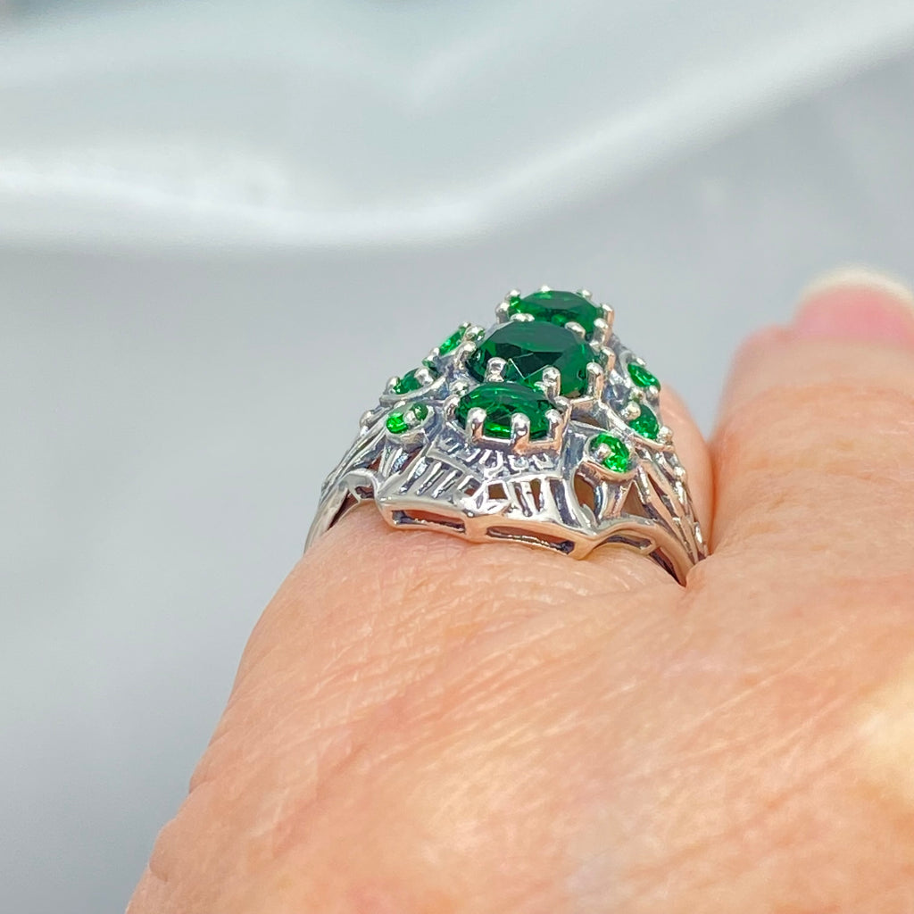 Emerald Ring with 9 Gems, sterling silver filigree, D69, 9-Gem Ring, Silver Embrace jewelry, Silver ring with green gemstones on a finger against a neutral background