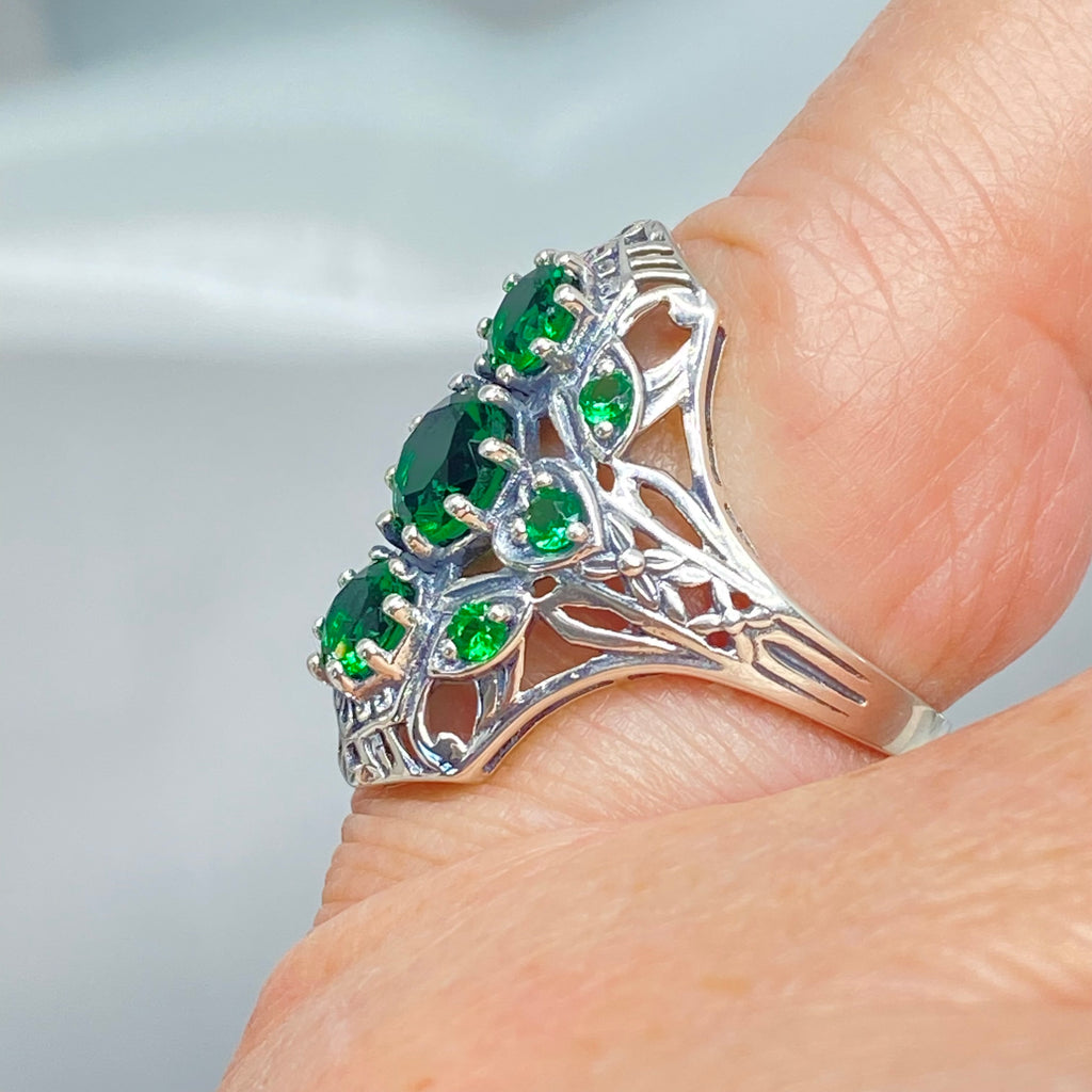 Emerald Ring with 9 Gems, sterling silver filigree, D69, 9-Gem Ring, Silver Embrace jewelry, Silver ring with green gemstones on a finger against a neutral background