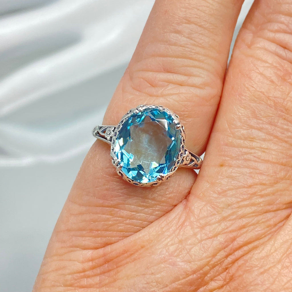 Silver ring with a blue topaz gemstone on a finger, Aquamarine Ring, Sky Blue simulated oval gemstone, Sterling Silver floral filigree, Edward design #D70z