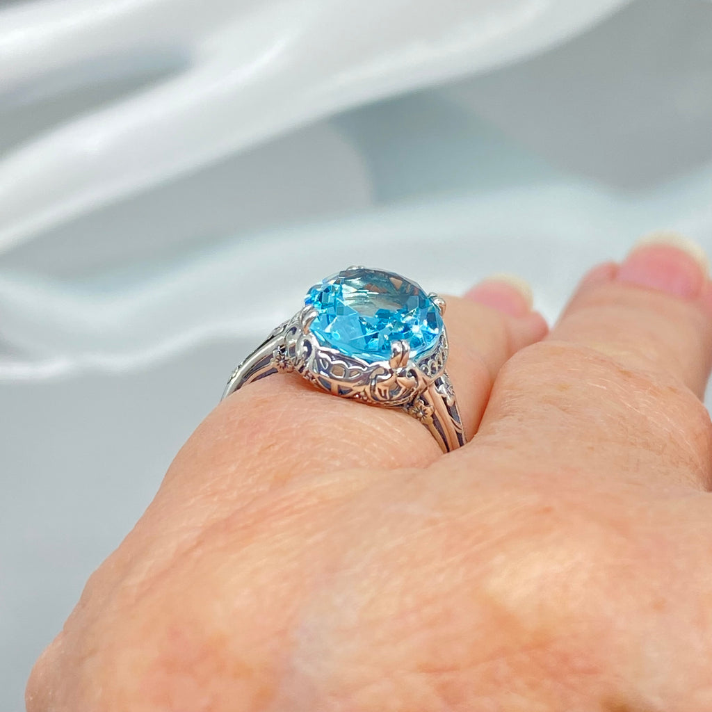 Silver ring with a blue topaz gemstone on a finger, Aquamarine Ring, Sky Blue simulated oval gemstone, Sterling Silver floral filigree, Edward design #D70z