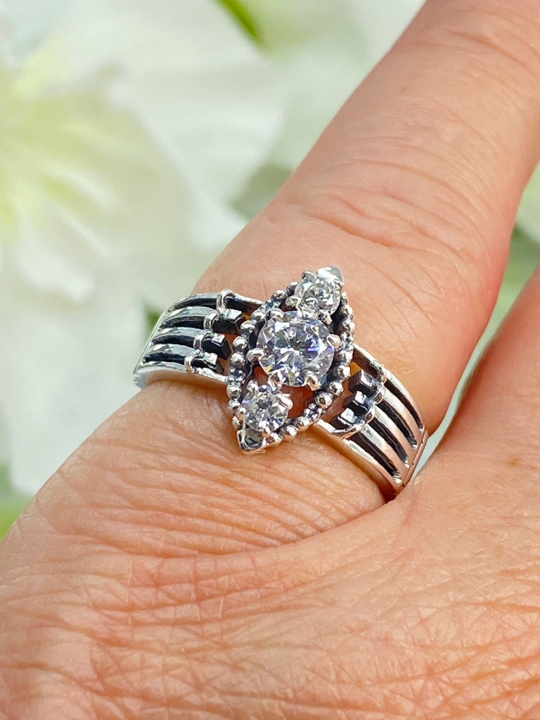 a close up of a person's hand with a ring on it a three stone ring with a White CZ center. Sterling Silver Art Deco Filigree, fine detail, Silver Embrace Jewelry, Xanadu D164