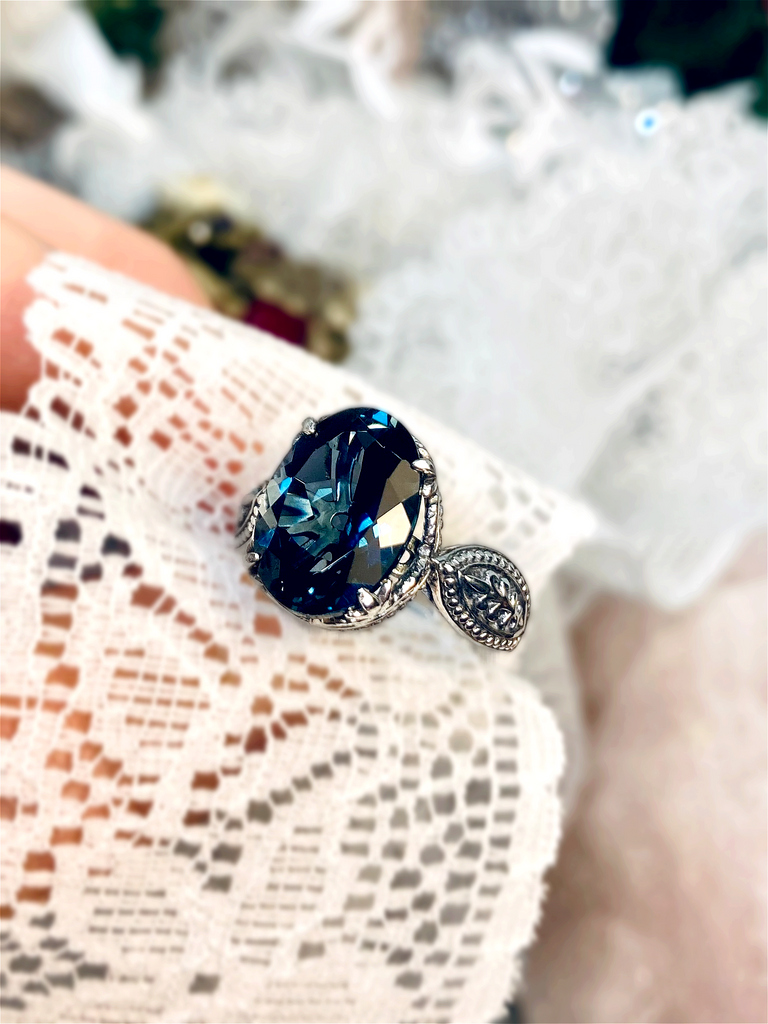 a woman's hand holding a ring with a blue stone
