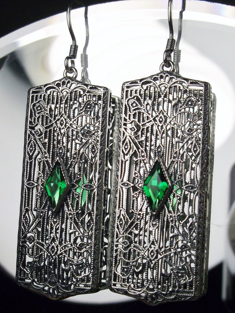 Rectangle Art Deco style earrings with fine lace filigree and a diamond shaped emerald green gemstone in the center of the lace filigree field, traditional shepherd hook style ear wire closures