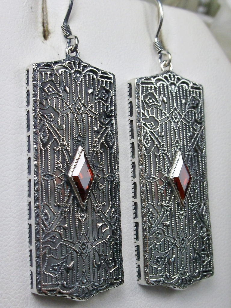 Rectangle Art Deco style earrings with fine lace filigree and a diamond shaped red garnet Cubic zirconia gemstone in the center of the lace filigree field, traditional shepherd hook style ear wire closures