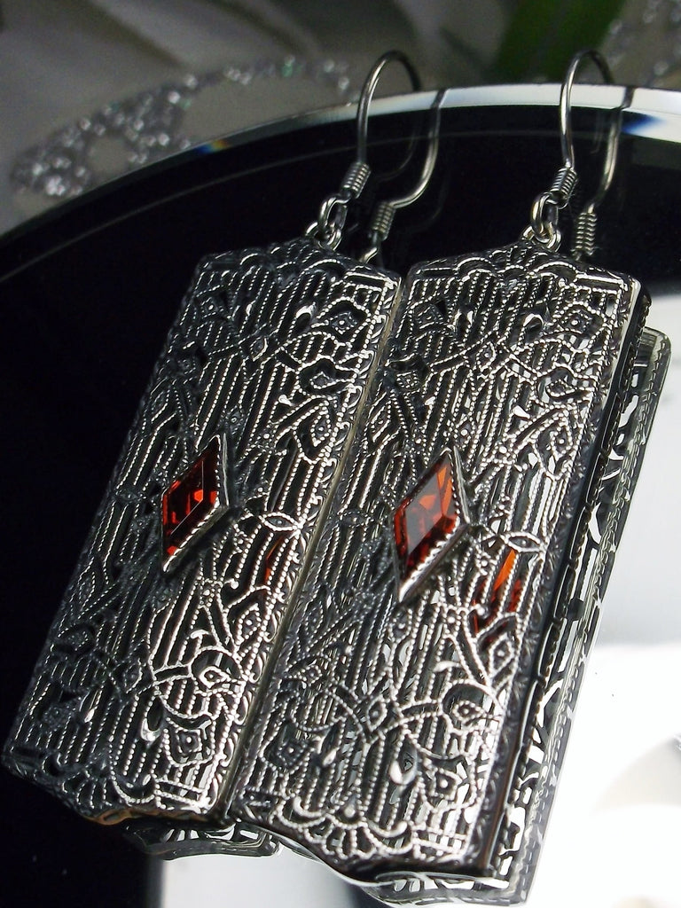 Rectangle Art Deco style earrings with fine lace filigree and a diamond shaped red garnet Cubic zirconia gemstone in the center of the lace filigree field, traditional shepherd hook style ear wire closures