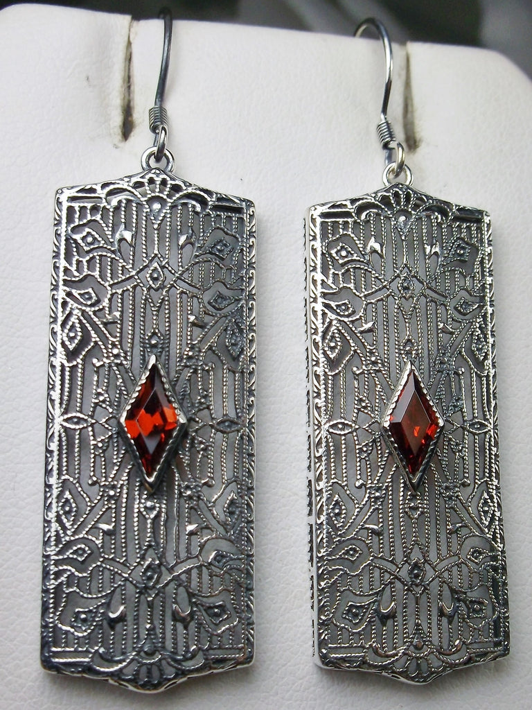 Rectangle Art Deco style earrings with fine lace filigree and a diamond shaped red ruby gemstone in the center of the lace filigree field, traditional shepherd hook style ear wire closures