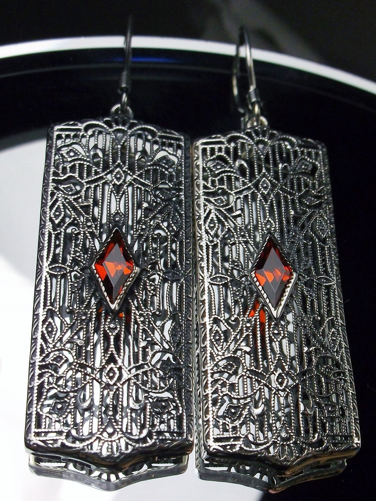 Rectangle Art Deco style earrings with fine lace filigree and a diamond shaped red ruby gemstone in the center of the lace filigree field, traditional shepherd hook style ear wire closures