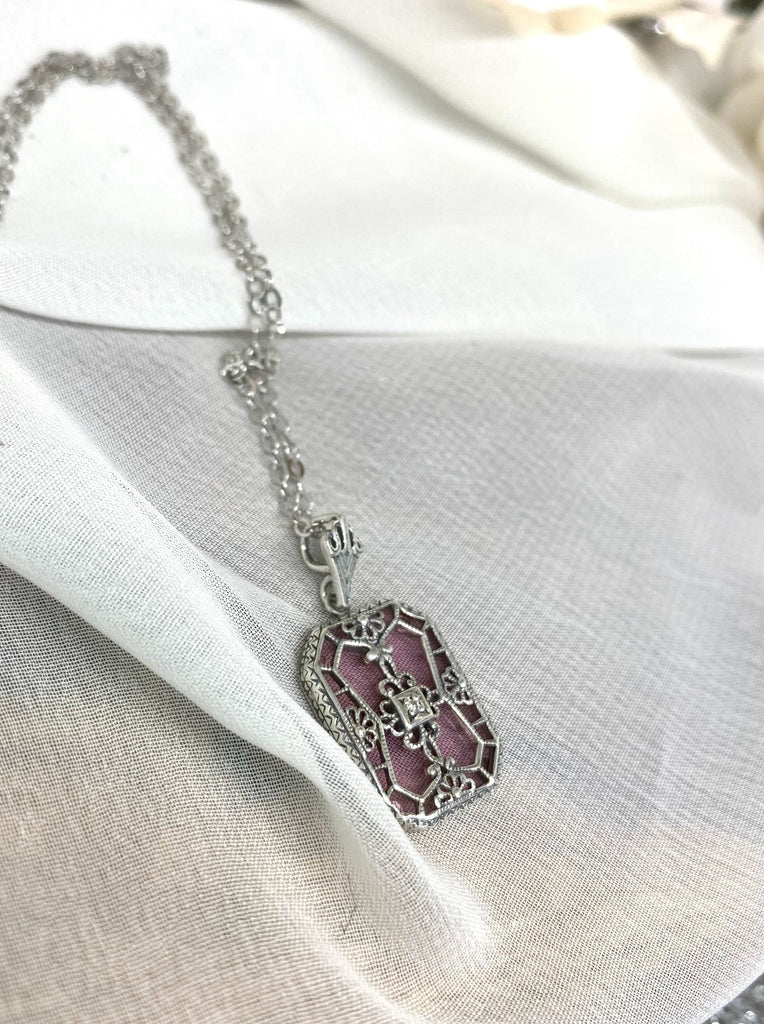 Pink Camphor Glass pendant with a CZ gem inset in the center, sterling silver filigree edging and across the glass face in window pane style