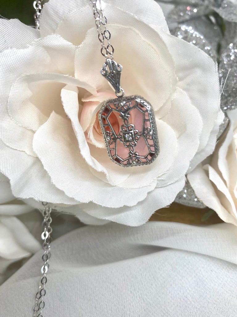 Pink Camphor Glass pendant with a CZ gem inset in the center, sterling silver filigree edging and across the glass face in window pane style