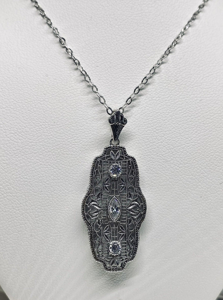 white CZ art deco pendant, center stone is marquise cut white CZ,  there are two white CZs above and below the center stone, delicate floral filigree surrounds all stones and edges the sides of the pendant