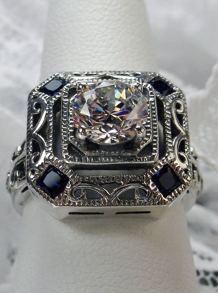 art deco style ring with a white CZ center stone and 4 deep blue gems in each corner of the octagonal filigree