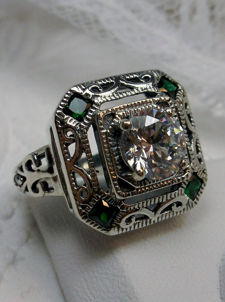 art deco style ring with a white CZ center stone and 4 emerald green gems in each corner of the octagonal filigree