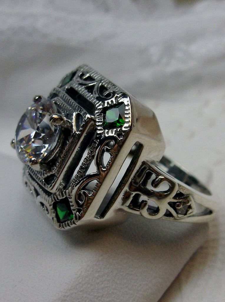 art deco style ring with a white CZ center stone and 4 emerald green gems in each corner of the octagonal filigree