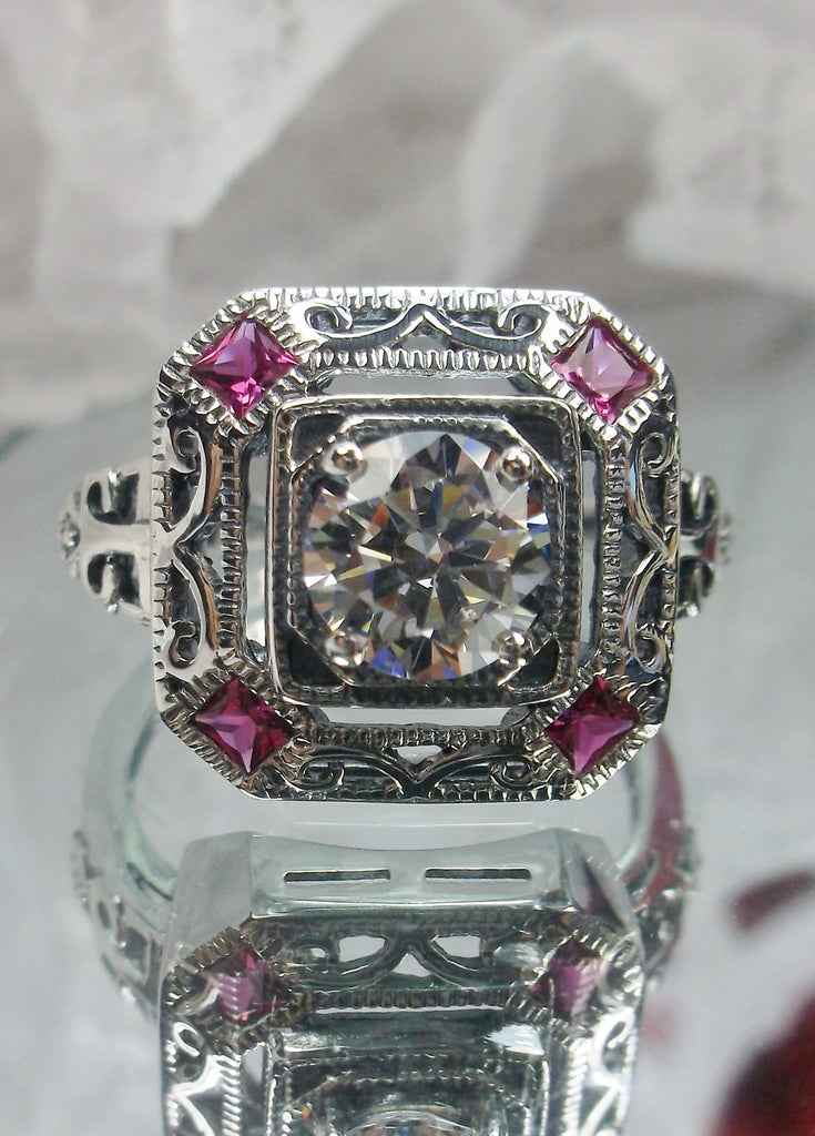 art deco style ring with a white CZ center stone and 4 ruby red gems in each corner of the octagonal filigree