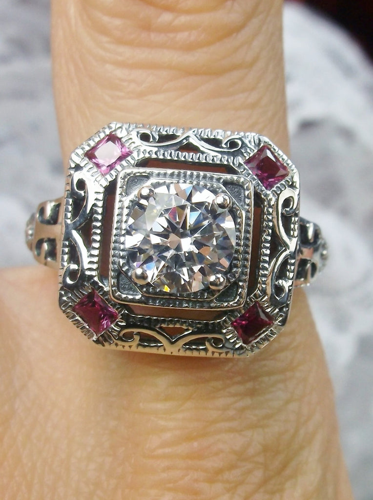 art deco style ring with a white CZ center stone and 4 ruby red gems in each corner of the octagonal filigree