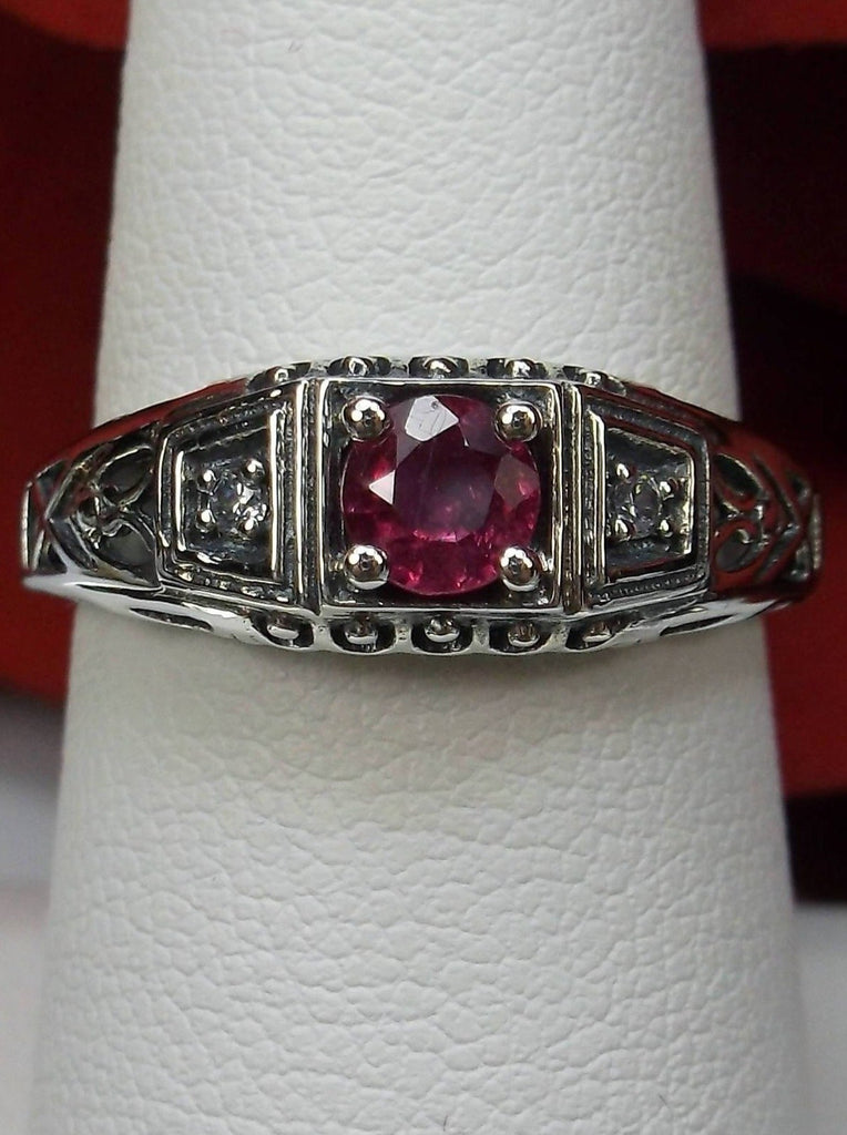 Art deco style ring with a natural ruby stone in the center, and two white CZ accents on either side set in sterling silver deco filigree