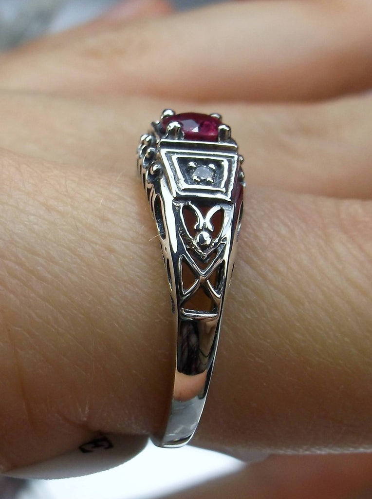 Art deco style ring with a natural ruby stone in the center, and two white CZ accents on either side set in sterling silver deco filigree