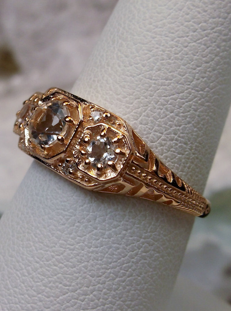 Art deco style ring with three natural white topaz gems set in rose gold filigree