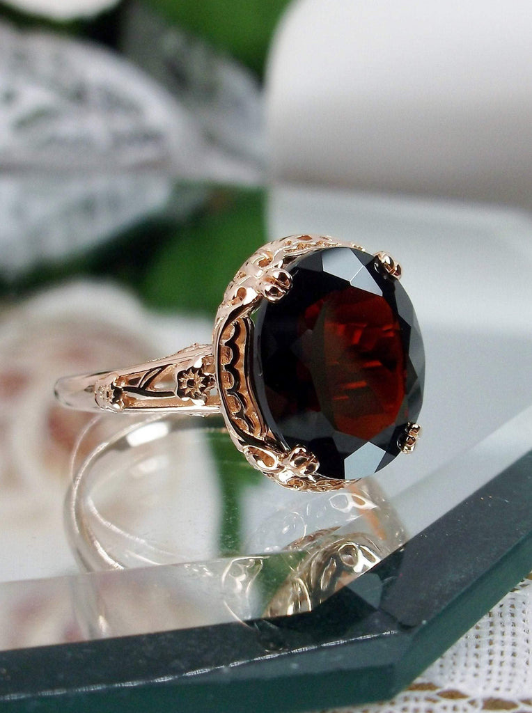 Natural Garnet Ring, Rose Gold over Sterling Silver, floral filigree setting and band, oval garnet stone, Edward design#70z, offset side front view on a mirror surface